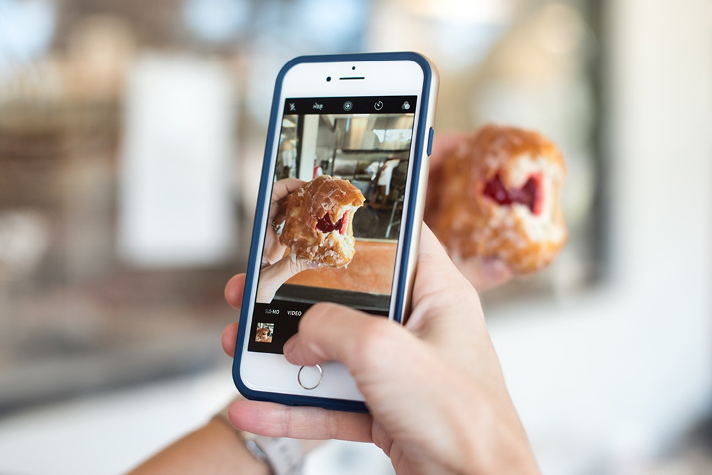 Hand holding a cell phone with a picture of a pastry